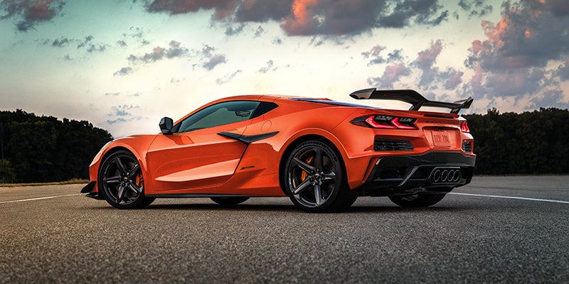An orange Chevrolet Corvette Z06 sports car on an asphalt road at sunset.
